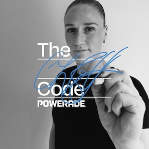 Zwart-witfoto van CJ Bott in een donker shirt die met een blauwe stift op het camerabeeld schrijft. Op de voorgrond staat de tekst “The Code POWERADE”.