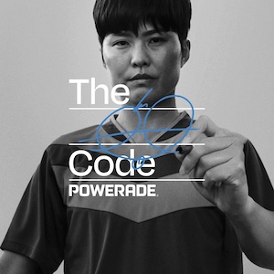 Zwart-witafbeelding van Ji So Yun in een sportshirt die met een marker iets in blauwe inkt schrijft over de tekst “The Code POWERADE”.